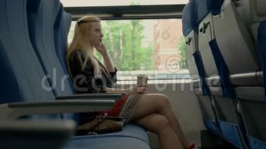 年轻漂亮的女人坐在火车上。 在火车上喝咖啡的女孩